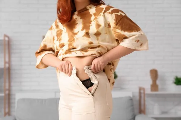 Image of woman trying to do her trousers up after pregnancy weight gain Aylesbury